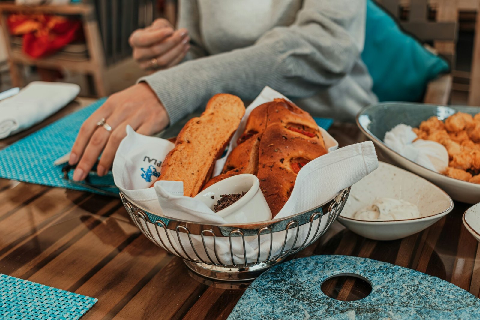 A woman sitting at a table with a basket of bread